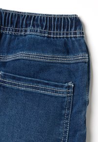 Blauwe denim stof met een geraffineerde elastische tailleband, inclusief een enkele achterzak en contrasterende witte stiksels.