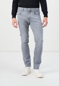 Helle graue Skinny-Jeans aus Denim, mit einem klassischen Fünf-Taschen-Design und einer dezenten Waschung. Getragen mit weißen Sneakern.