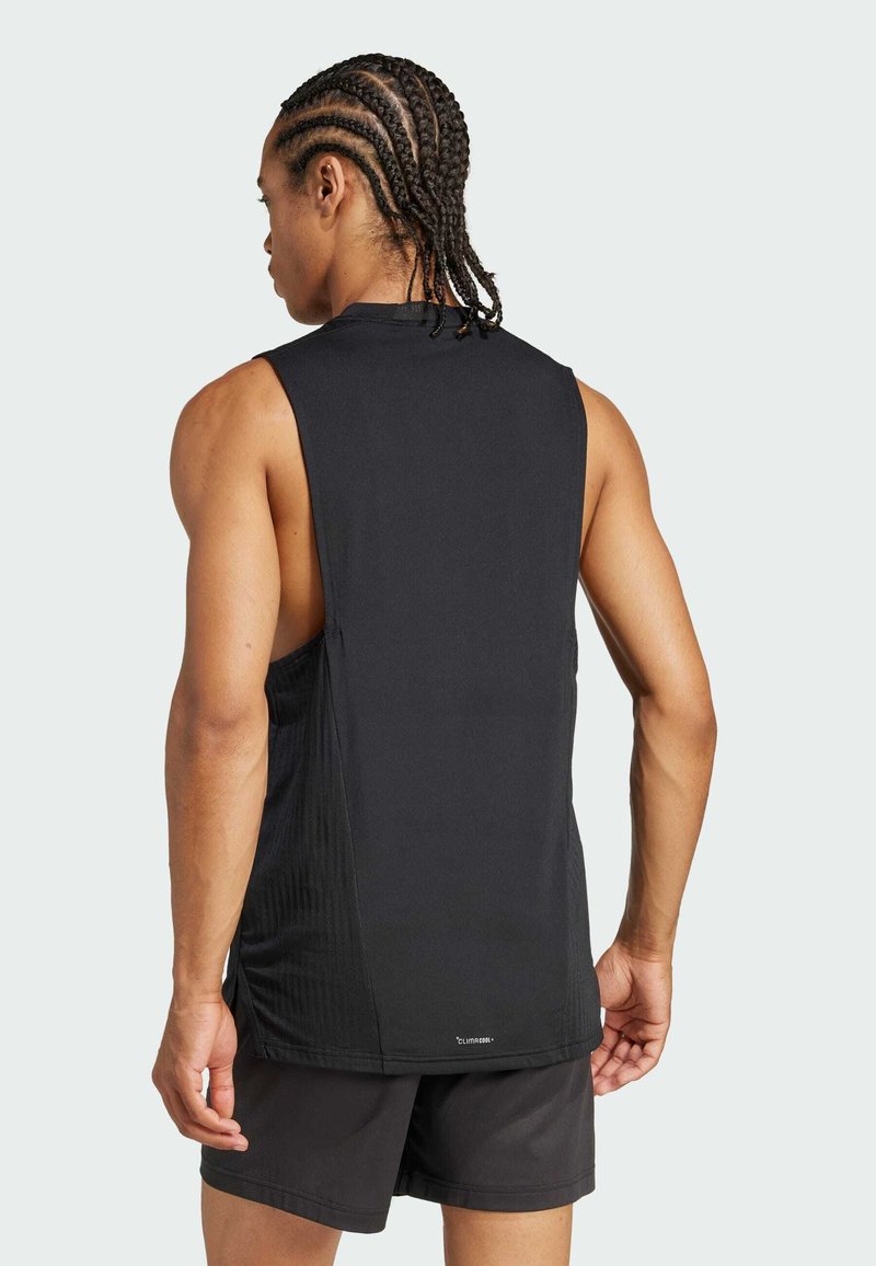 Camiseta atlética sin mangas negra con un panel texturizado en los laterales. Tela ligera, corte holgado y diseño minimalista.