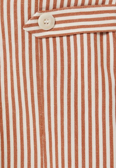 Camisa a rayas con líneas alternas estrechas en naranja y blanco, confeccionada en tela ligera y con un único botón a juego en un bolsillo.