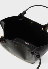 Borsa tote in pelle nera con finitura texturizzata. Dotata di accessori in oro, un interno spazioso e manici annodati come dettaglio. L'interno include un piccolo portafoglio.