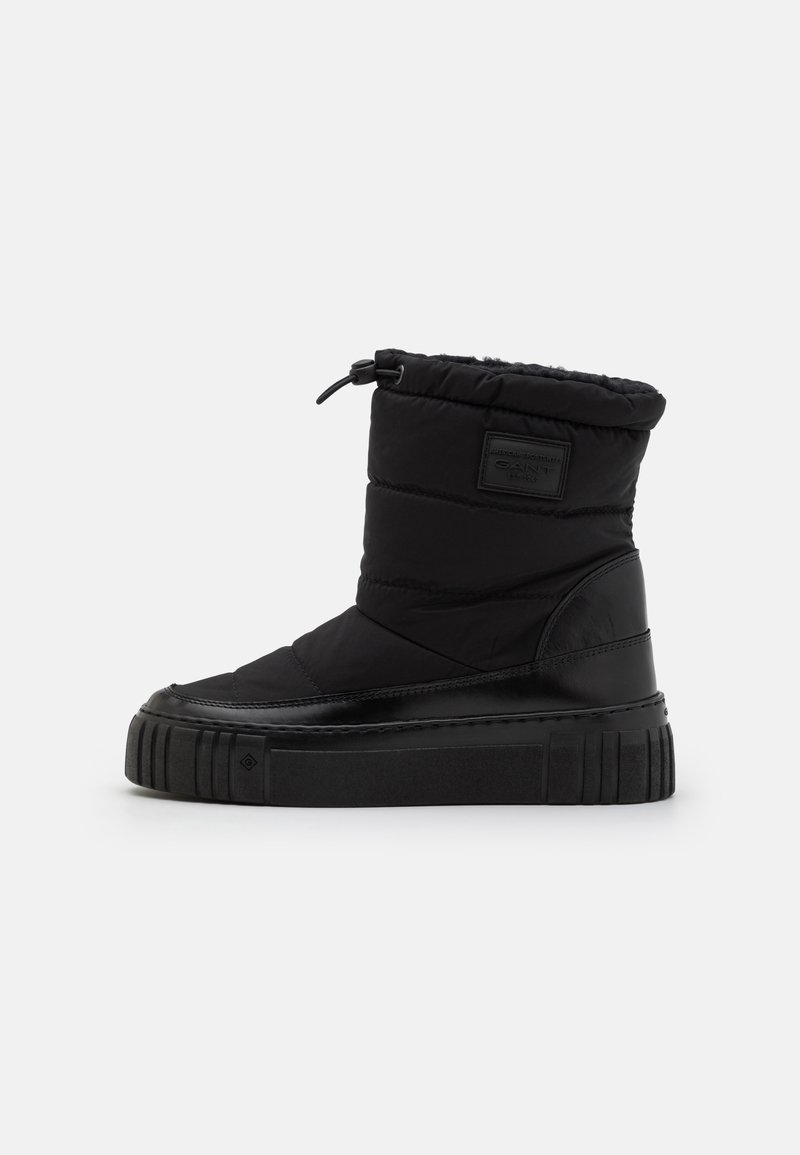 Black padded ankle boots with a textured leather base, elasticized cuff, and a chunky rubber sole featuring horizontal grooves.