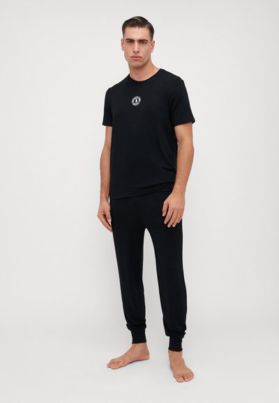 Czarny bawełniany t-shirt z krótkim rękawem, okrągłym dekoltem i małym logo, w parze z dopasowanymi czarnymi spodniami dresowymi z mankietami.