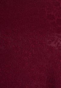 Texturovaná tkanina v burgundské barvě s květinovým vzorem, s měkkým a hladkým povrchem a jemným leskem, vhodná pro čalounění nebo oděvy.
