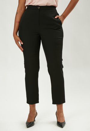 Pantaloni neri su misura con vestibilità slim, dotati di chiusura frontale con bottone, tasche laterali e una finitura liscia. Orlati appena sopra la caviglia.