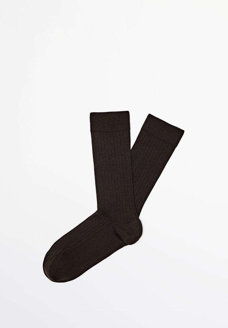 Ett par svarta ribbade ankelsockor liggande platt, som visar full längd och fotform på en vit bakgrund.
