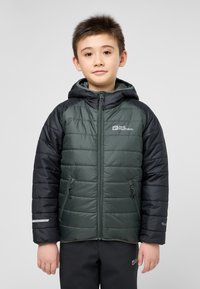 Giacca imbottita con corpo verde e maniche nere, dotata di cappuccio, tasche con zip e dettagli riflettenti. Progettata per il calore.