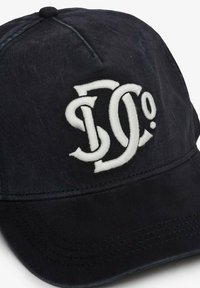 Sort cap lavet af bomuld med en buet skygge, der har et fremtrædende hvidt broderet logo på forsiden. Blød tekstur, justerbar rem.