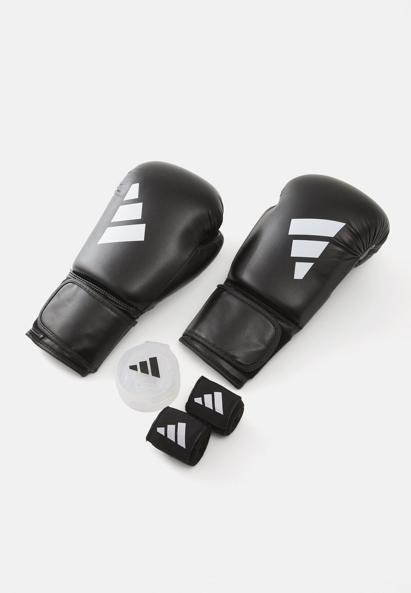 Black boxing gloves made of synthetic leather with grey accents, alongside a container and two black wrist wraps.