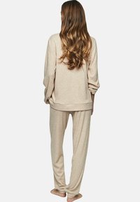 Beige geribbelde brei loungewear set met een relaxed-fit lange mouw top en bijpassende broek, ontworpen met een comfortabele silhouet en zachte textuur.