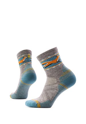 Par de calcetines grises y azules con diseño de perro naranja corriendo y detalles amarillos, mostrados desde ángulos laterales sobre un fondo blanco.