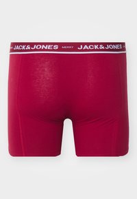 Rote Baumwoll-Boxershorts mit einem schwarzem und weißen Logo-Bund, die eine enganliegende Passform, eine glatte Textur und keine sichtbaren Muster oder Akzente aufweisen.