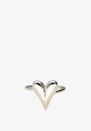Anillo de plata con un diseño liso y brillante en forma de corazón en el centro, sobre un fondo blanco sencillo.