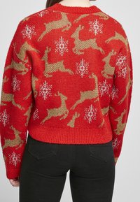 Roter Strickpullover mit Rentiermuster in Gold und Weiß, mit geripptem Saum und Bündchen. Für eine lockere Passform entworfen.