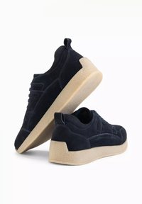 Baskets en suède bleu marine avec une languette en tissu texturé, des coutures marquées et une semelle en caoutchouc beige clair. Dispose d'un onglet de traction au niveau du talon.
