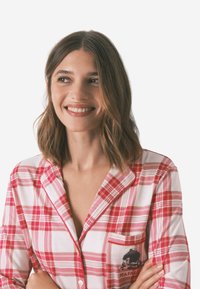 Camicia da pigiama a quadri rossi e bianchi con una tasca che presenta una grafica nera. Tessuto morbido, dettagli con bottoni e design del colletto classico.