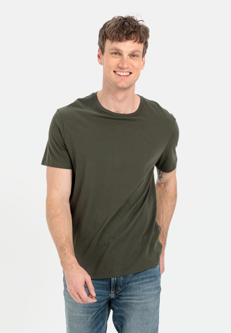 Olivenfarvet bomulds T-shirt med korte ærmer og rund hals, med et diskret logo og en glat tekstur, parret med blå jeans.