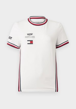 Fehér rövid ujjú póló piros, fekete és fehér csíkos szegéllyel a galléron, ujjakon és oldalakon, Cadillac Formula 1 és Tommy Hilfiger logókkal.