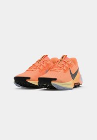 Nike hardloopschoenen met een ademend oranje mesh bovenwerk, zwarte accenten, een gestructureerde zool en een glad, gebogen ontwerp.