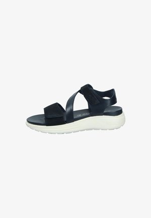 Black sandal featuring cross-strap design, suede and faux leather materials, cushioned white sole, and adjustable Velcro fasteners.