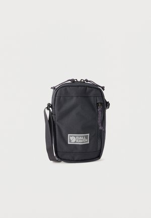 Bolso bandolera compacto negro de Fjällräven con bolsillo delantero con cremallera y correa ajustable sobre fondo liso.
