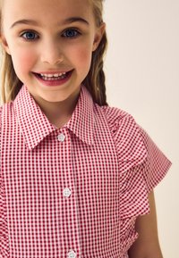 Rot-weiße kariertes Hemd mit Kragen, Puffärmeln und weißen Knöpfen auf der Vorderseite. Weicher Stoff mit Gingham-Muster.