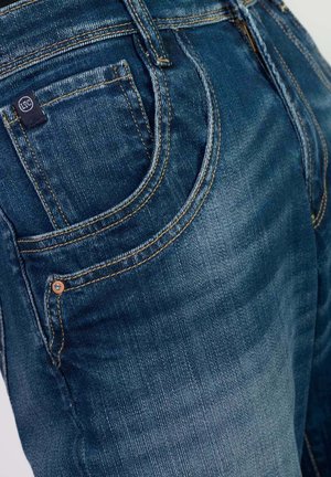 Donkerblauwe denim jeans met een gestructureerde afwerking. Kenmerken zijn onder andere zichtbare stiksels, een klein logo op de achterzak en een klassieke snit.
