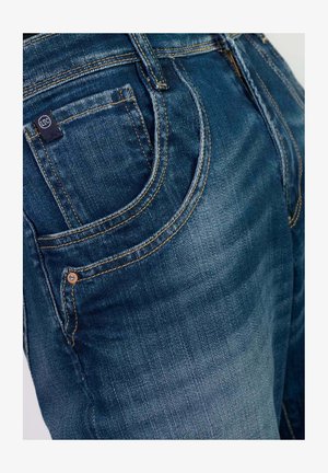 Jeans in denim di colore blu scuro con una finitura testurizzata. Le caratteristiche includono cuciture visibili, un piccolo logo sulla tasca posteriore e un taglio classico.