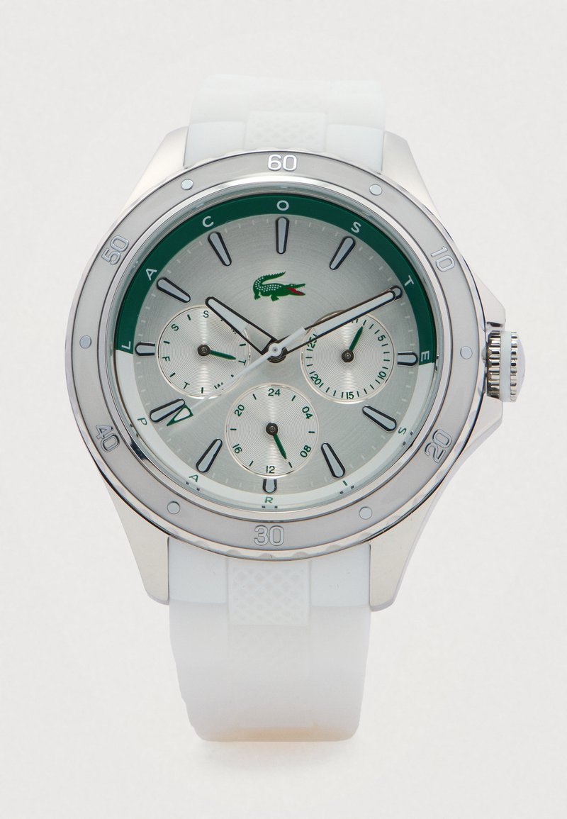 Montre avec cadran argent et vert, trois sous-cadrans et bracelet en silicone blanc, affichant 11:10:38, avec le logo crocodile de Lacoste.