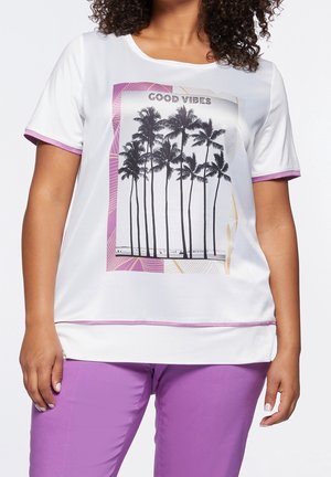 Haut blanc à manches courtes avec des accents violets, arborant une impression graphique de palmiers et le texte "GOOD VIBES" dans un design rectangulaire.