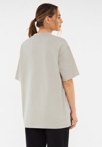 Szürke, oversized rövid ujjú póló, puha pamutból készült. Klasszikus kerek nyakkivágás jellemzi és laza fazonú. Nincsenek látható minták.