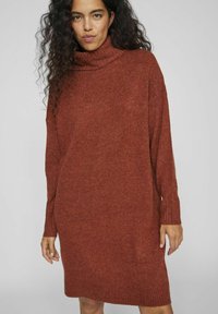 Pletené oversized svetr šaty v spáleně oranžové, s ribbaným rolákem a manžetami, s jemnou texturou a rovnou siluetou.