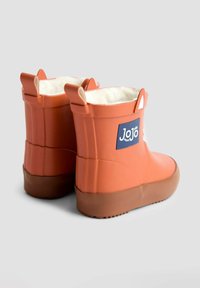 Bottes en caoutchouc orange avec une doublure blanche douce, des semelles marron et des poignées sur les côtés. Présente un patch logo bleu sur le côté extérieur.