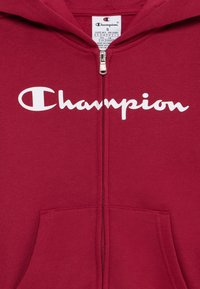 Rote zip-up Hoodie aus Baumwollmischung. Merkmale das weiße "Champion"-Logo, einen Frontreißverschluss und eine Kängurutasche. Weicher Stoff, lässiges Design.