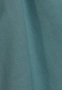 Tissu turquoise avec un tissage texturé, présenté en diagonale, mettant en valeur sa surface lisse et son motif cohérent tout au long.