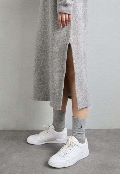 Grijze, gebreide midi-jurk met zijsplitten, gecombineerd met witte sneakers en grijze ribgebreide sokken. Gladde textuur en casual ontwerp.