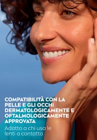 Primo piano di un volto sorridente con capelli ricci castani, tonalità della pelle naturale e una mano che tocca la guancia. Lo sfondo presenta un cielo blu.