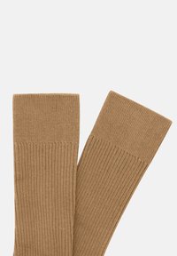 Calcetines de canalé hasta la rodilla en color marrón, hechos de una tela suave con un patrón texturizado. Presenta un puño sólido y ancho en la parte superior.