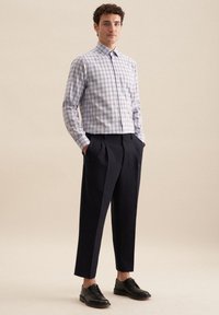 Lichtblauw en wit geruit overhemd met een spread collar, gecombineerd met donkere geplooide broeken en zwarte leren schoenen.
