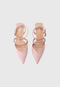 Ροζ μυτερές γόβες με λουράκι στον αστράγαλο, με ρύθμιση από κρύσταλλα. Ομαλή υφή με γυαλιστερό φινίρισμα.