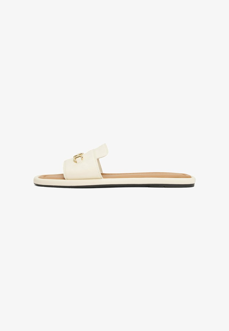 Slipper sandal in cream leather with a wide strap and gold buckle detail. Flat sole with black edge and tan footbed for comfort.