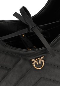 Black leather handbag with chevron stitching, featuring a gold-tone dual bird design pendant and a central black ribbon detail.