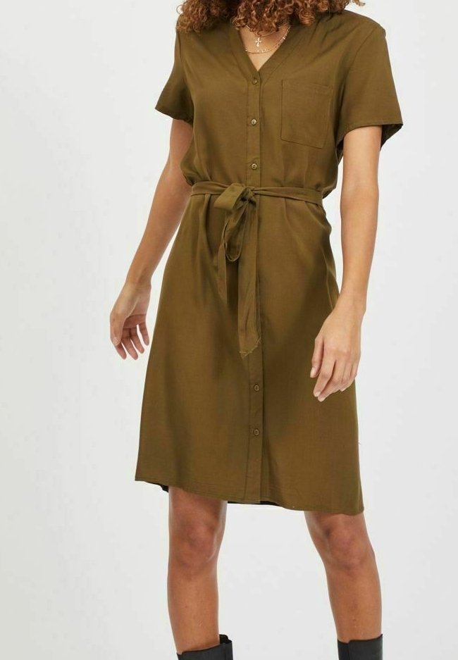 Robe courte à manches courtes vert olive avec un devant boutonné, un col en V, une ceinture à la taille et une poche poitrine. Tissu doux et coupe décontractée.