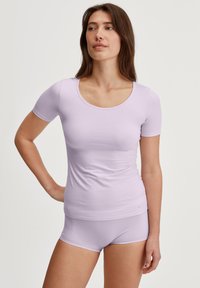 Lila T-shirt met korte mouwen en een ronde hals, gemaakt van zachte stof. Gecombineerd met bijpassende hipster-shorts. Glad textuur.