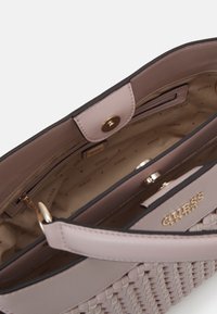 Vævet læder håndtaske i lys lilla med et guld logo på forsiden, og den har et beige stofinteriør samt en lynlåslomme.