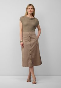 Strickoberteil mit einem Schalkragen, kombiniert mit einem knielangen, beigen Rock mit Knopfleiste. Der Rock hat einen seitlichen Schlitz und ist aus leichtem Stoff.