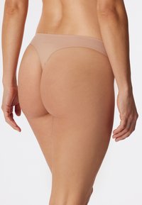 String nu en tissu doux et lisse. Couverture minimale avec une taille fine et un design sans coutures pour un look et une sensation épurés.