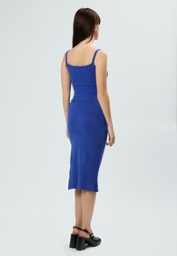 Blaues gestricktes Kleid mit tailliertem Oberteil und Midi-Länge; hat eine gerippte Textur an der Taille und am Saum, ergänzt durch dünne Träger.