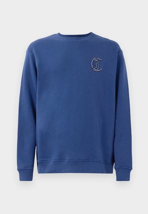 Sudadera azul de cuello redondo con mangas largas y una pequeña letra "C" bordada en negro y blanco en el lado izquierdo del pecho.