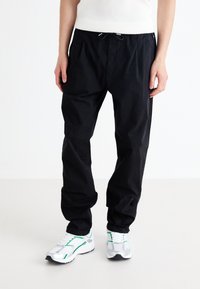 Pantalons décontractés noirs avec taille élastique et cordon de serrage. Fabriqués en tissu léger, présentant une coupe décontractée et un effilage aux chevilles.